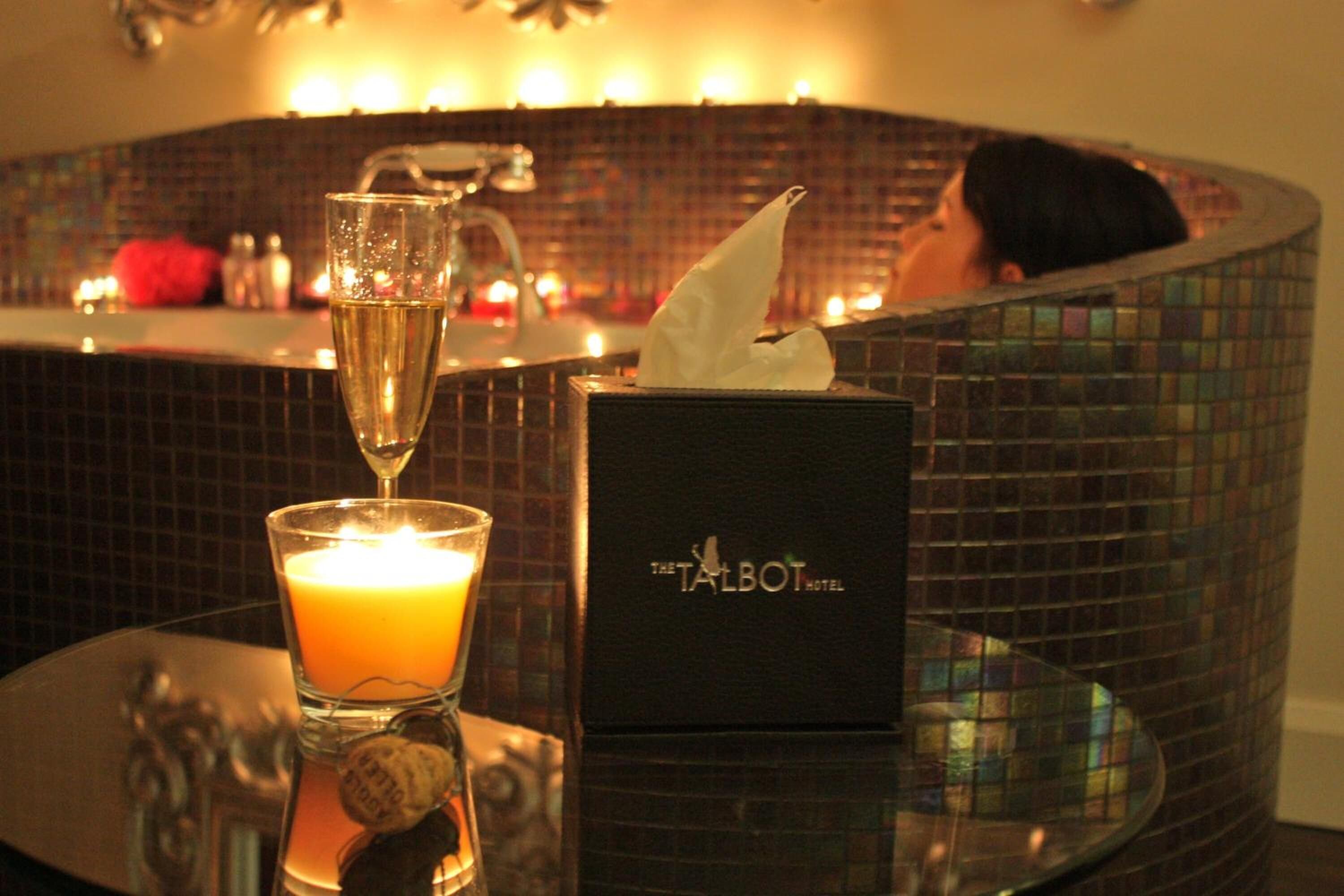 Un coin bar avec une bougie, une coupe de champagne et une boîte de mouchoirs portant l’inscription « The Talbot Hotel ».