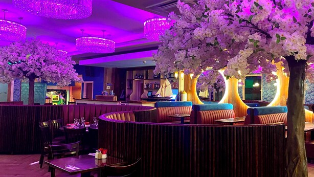 A restaurant with round seating, a bar area, and decorative lighting. - Talbot Hotel (Belmullet)