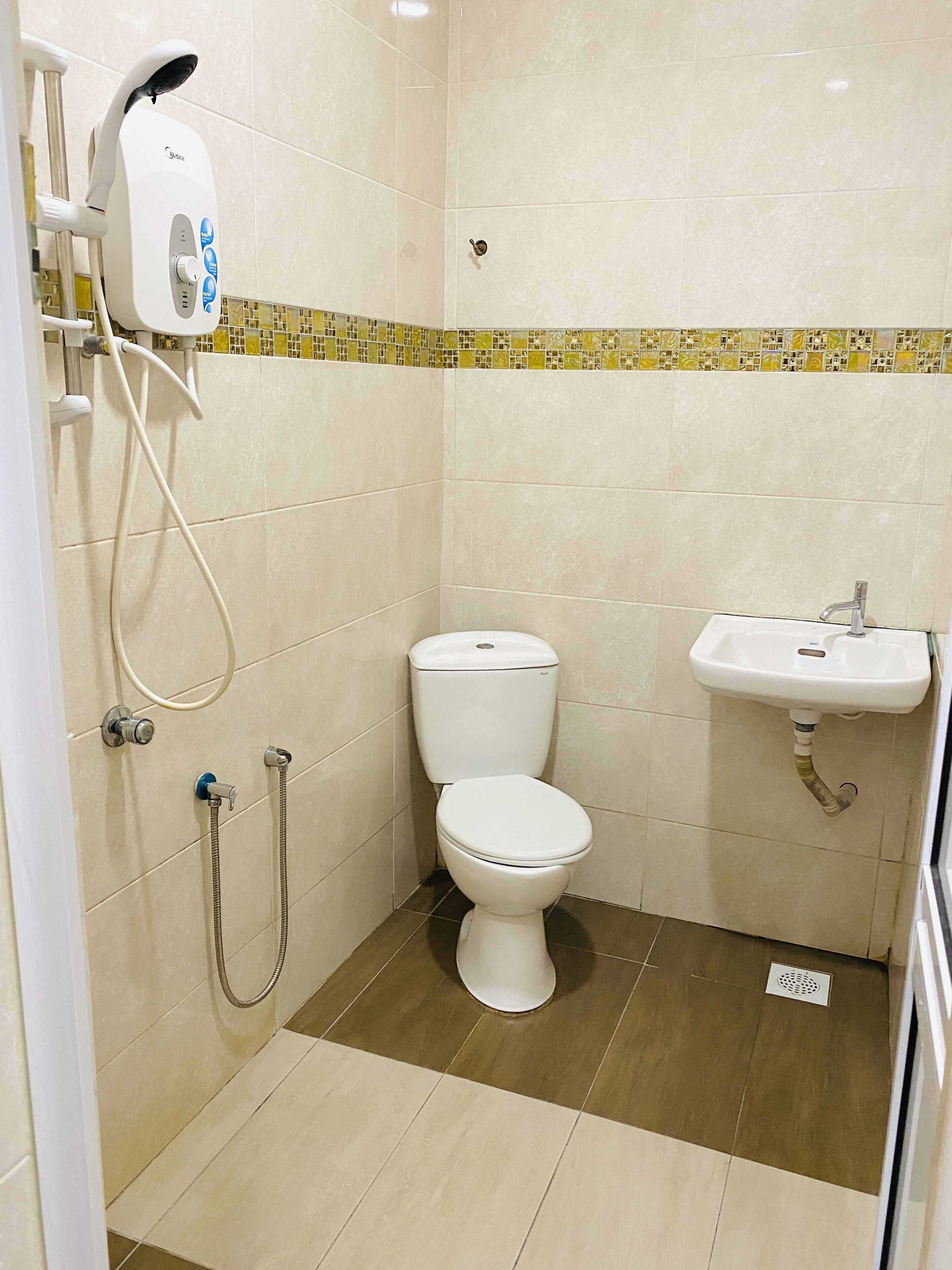A bathroom with a toilet, a sink, and a shower with a handheld showerhead.