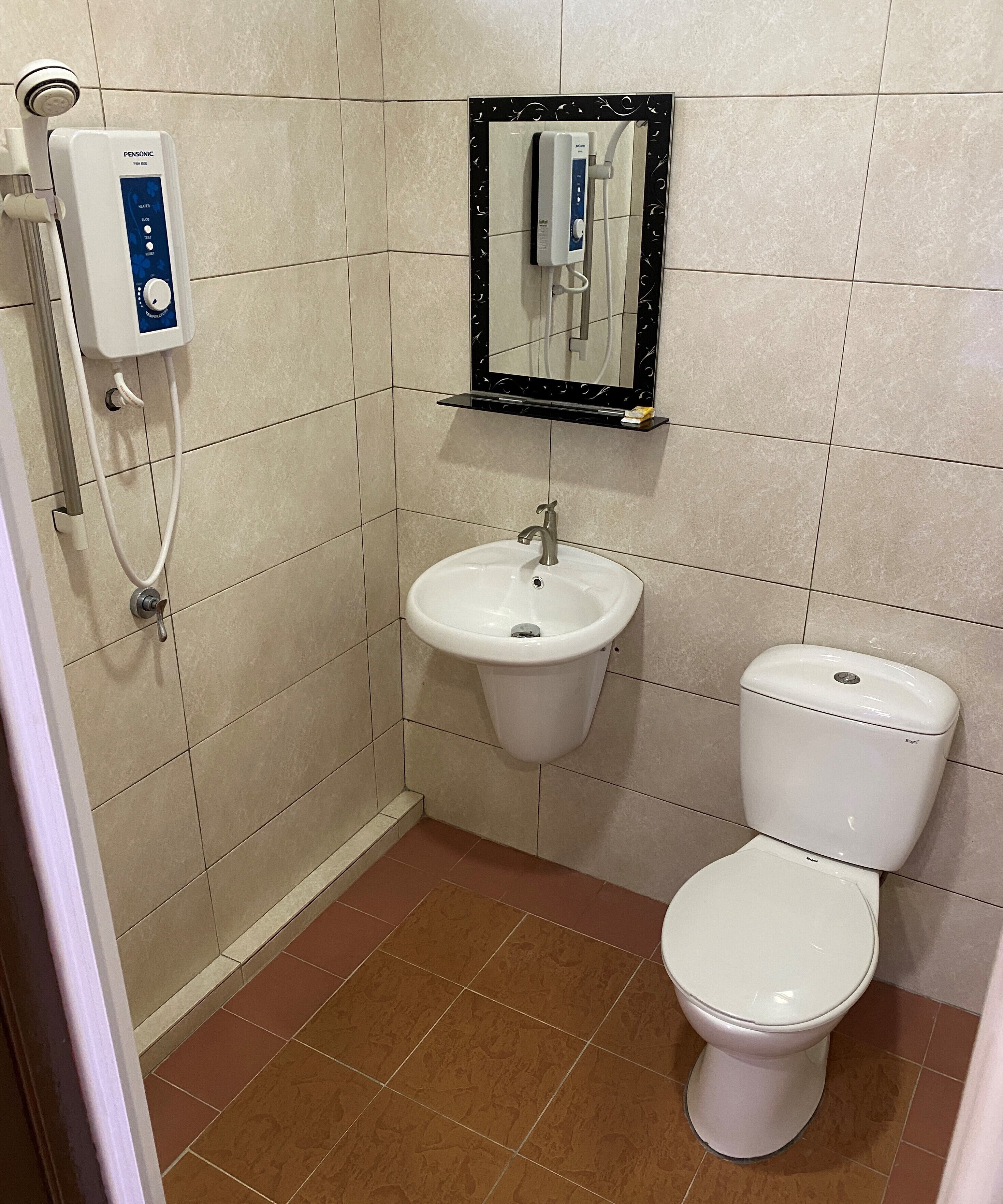 Un baño con ducha, lavabo, inodoro y espejo.