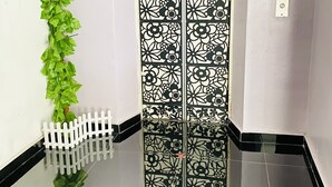 A hallway with a decorative door, a white picket fence, and a green plant. - Sunsega Hotel (Perai)