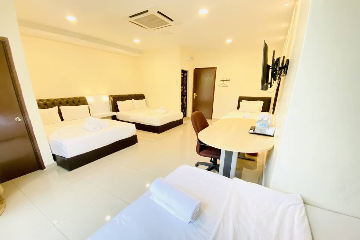 Une chambre d’hôtel avec deux lits simples, une table de salle à manger ronde, une chaise et un téléviseur fixé au mur.
