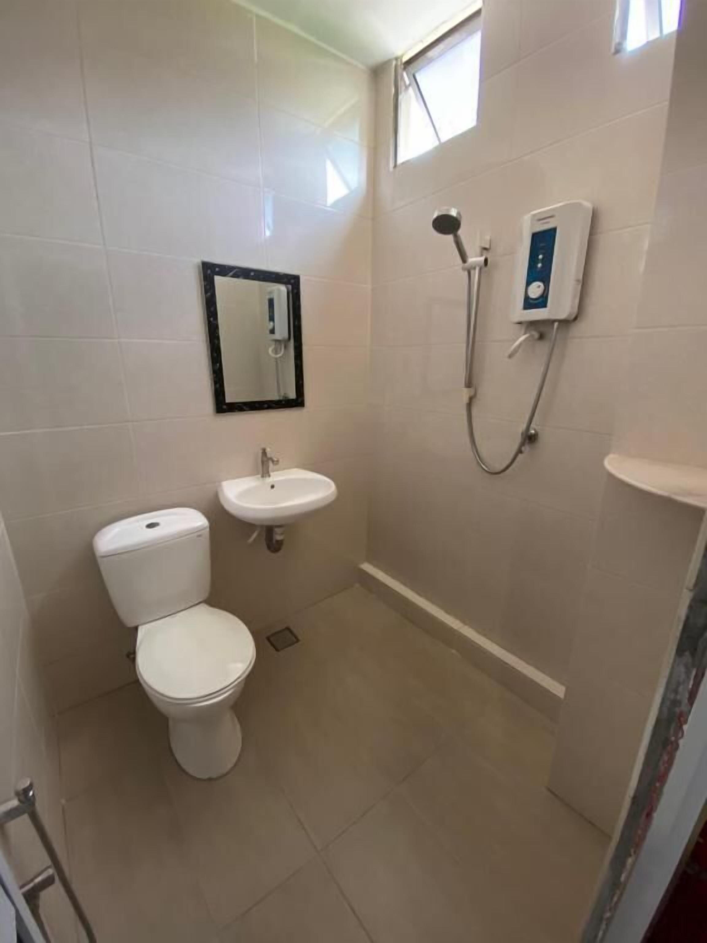 A small bathroom with a toilet, sink, and shower.