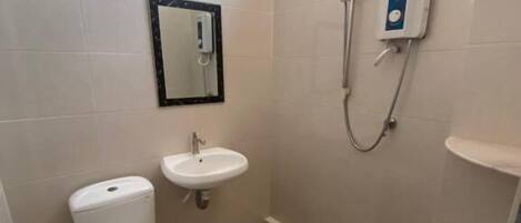 A small bathroom with a toilet, sink, and shower.