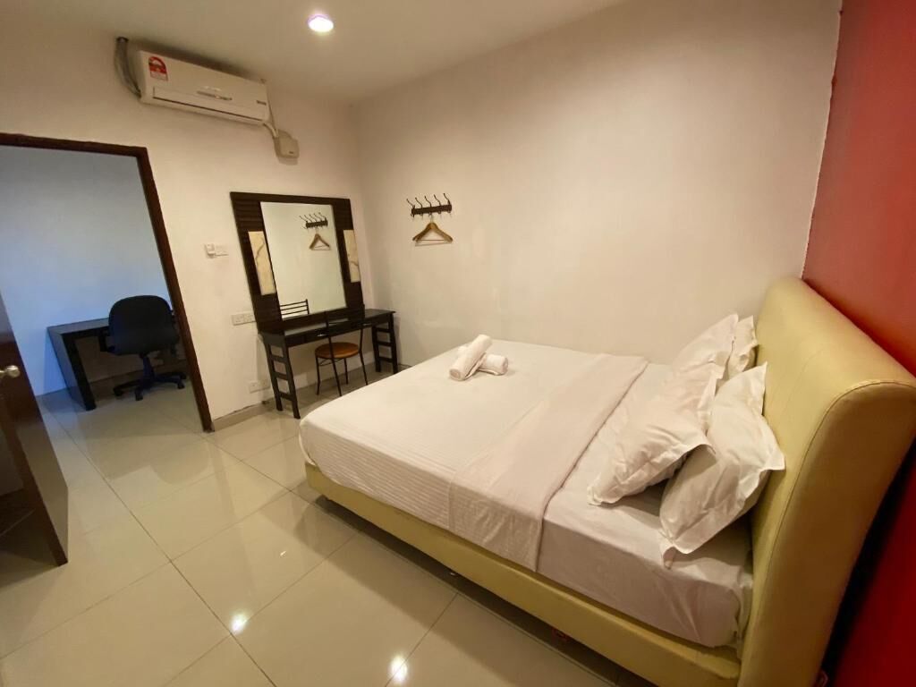Una habitación de hotel con cama, escritorio, silla, espejo y aire acondicionado.