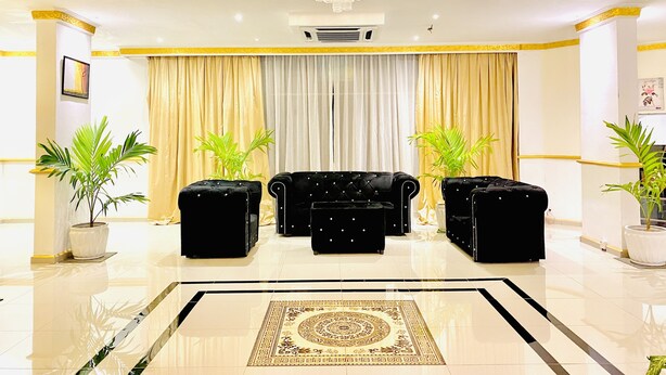 A spacious lobby with a chandelier, two black sofas, a patterned rug, and potted plants. - Sunsega Hotel (Perai)
