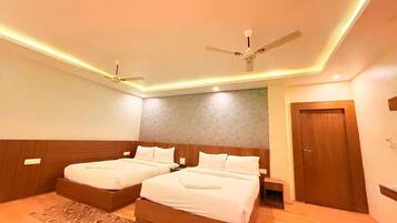 A hotel room with two beds, a ceiling fan, and a wooden door.