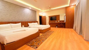 A hotel room with two beds, a wooden floor, a large mirror, and a TV. - Hotel Little Buddha (Lumbini)
