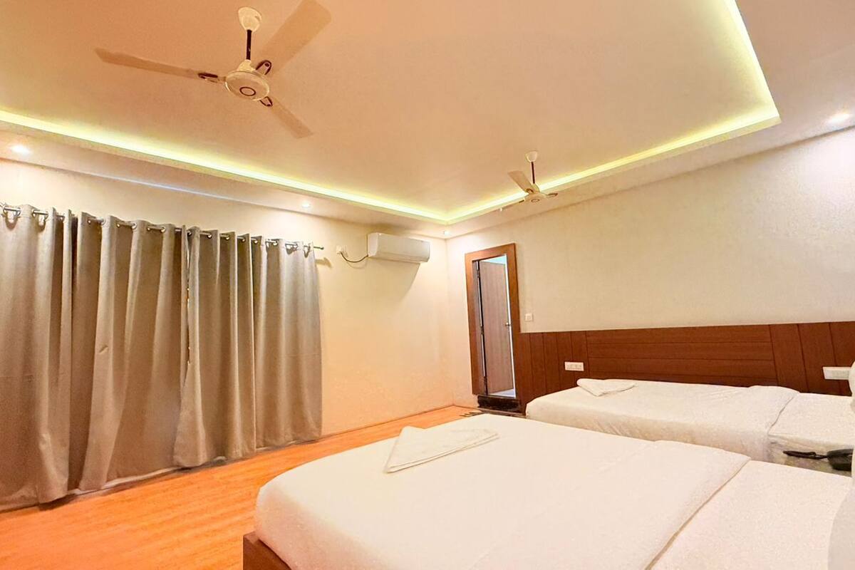 A hotel room with two beds, a ceiling fan, and a wooden headboard.