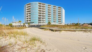 A beachfront hotel with a curved facade, multiple balconies, and a sandy beach in the foreground. - Beachfront Condo w/ Pool Access in Biloxi! (Biloxi)