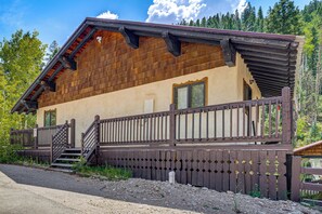 Eine Holzhütte mit Balkon, Treppe und Blick auf den umliegenden Wald.