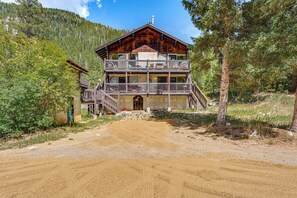 Eine zweistöckige Holzhütte mit Balkon, umgeben von Wald.