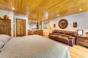Un dormitorio con una cama grande, un sofá de cuero y un techo de madera.