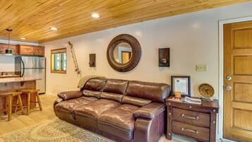 A spacious living area with a leather sofa, wooden ceiling, and a dining area with a refrigerator.
