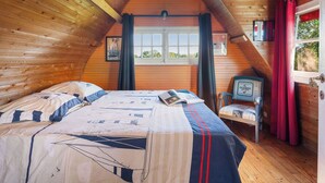 Um quarto de cabana acolhedor, com uma cama, uma janela e uma cadeira.