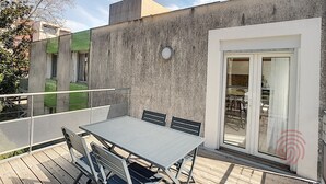 Eine Terrasse mit Tisch und Stühlen, eine Glastür zum Verschieben und eine Betonmauer.