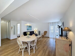 Un coin repas avec une table ronde, des chaises blanches, un luminaire suspendu et un tableau au mur.