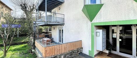 Un edificio moderno con balcón, pared de piedra y terraza de madera.