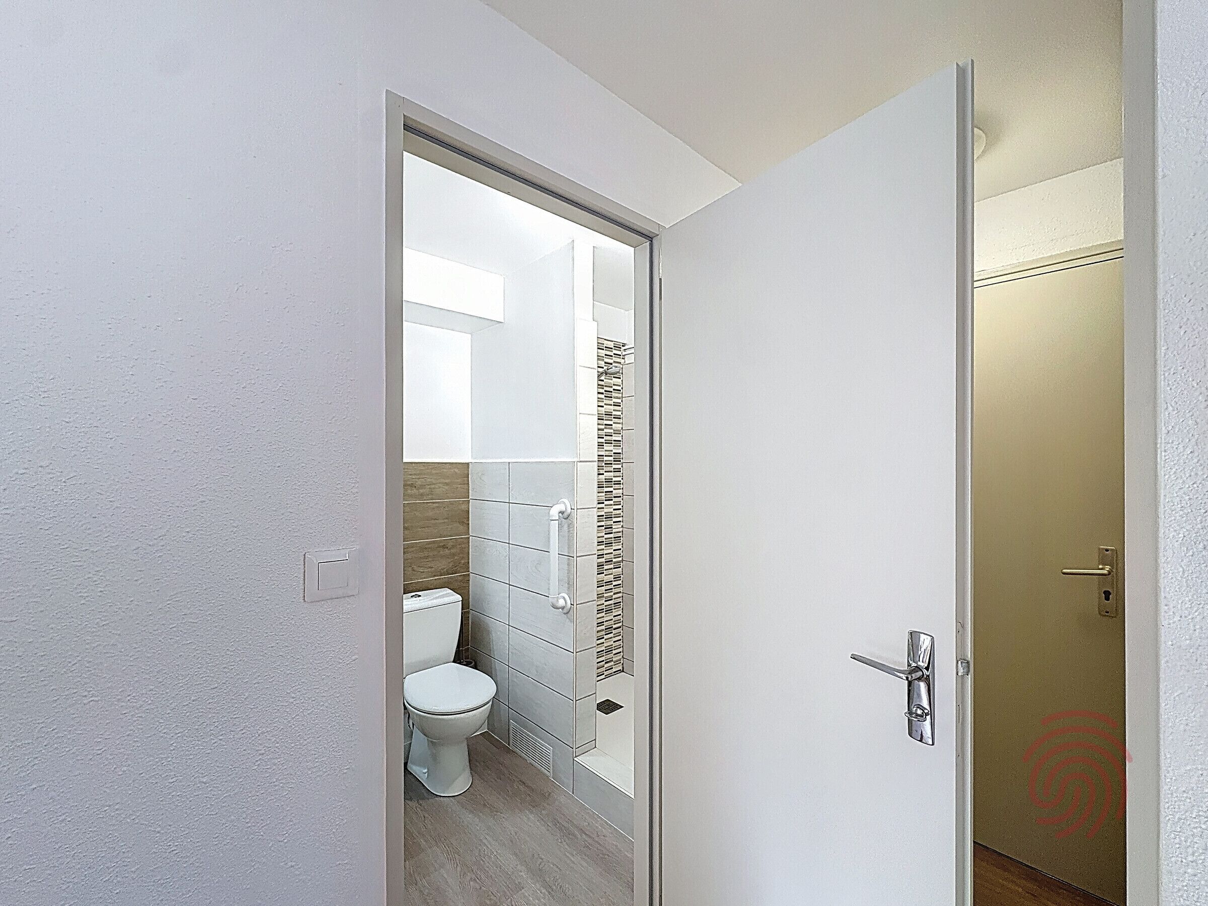 A modern bathroom with a toilet, shower, and a glass partition.