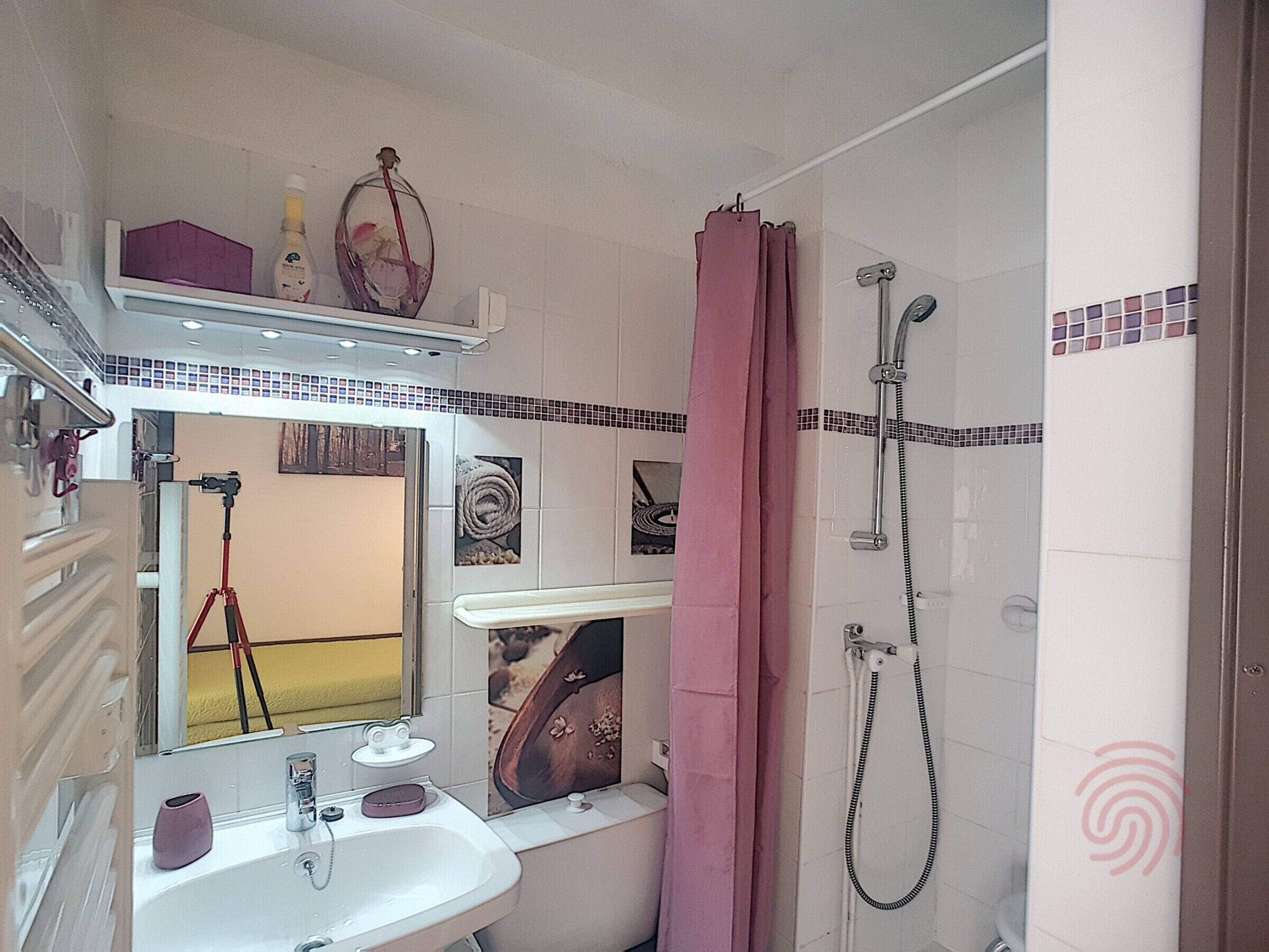 Een badkamer met een wastafel, spiegel, douche en een roze gordijn.