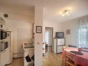 A compact kitchen with a stove, sink, and refrigerator. There is a dining area with a table and chairs.
