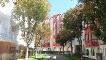 A courtyard with a pathway, benches, and a building with red and white architecture.