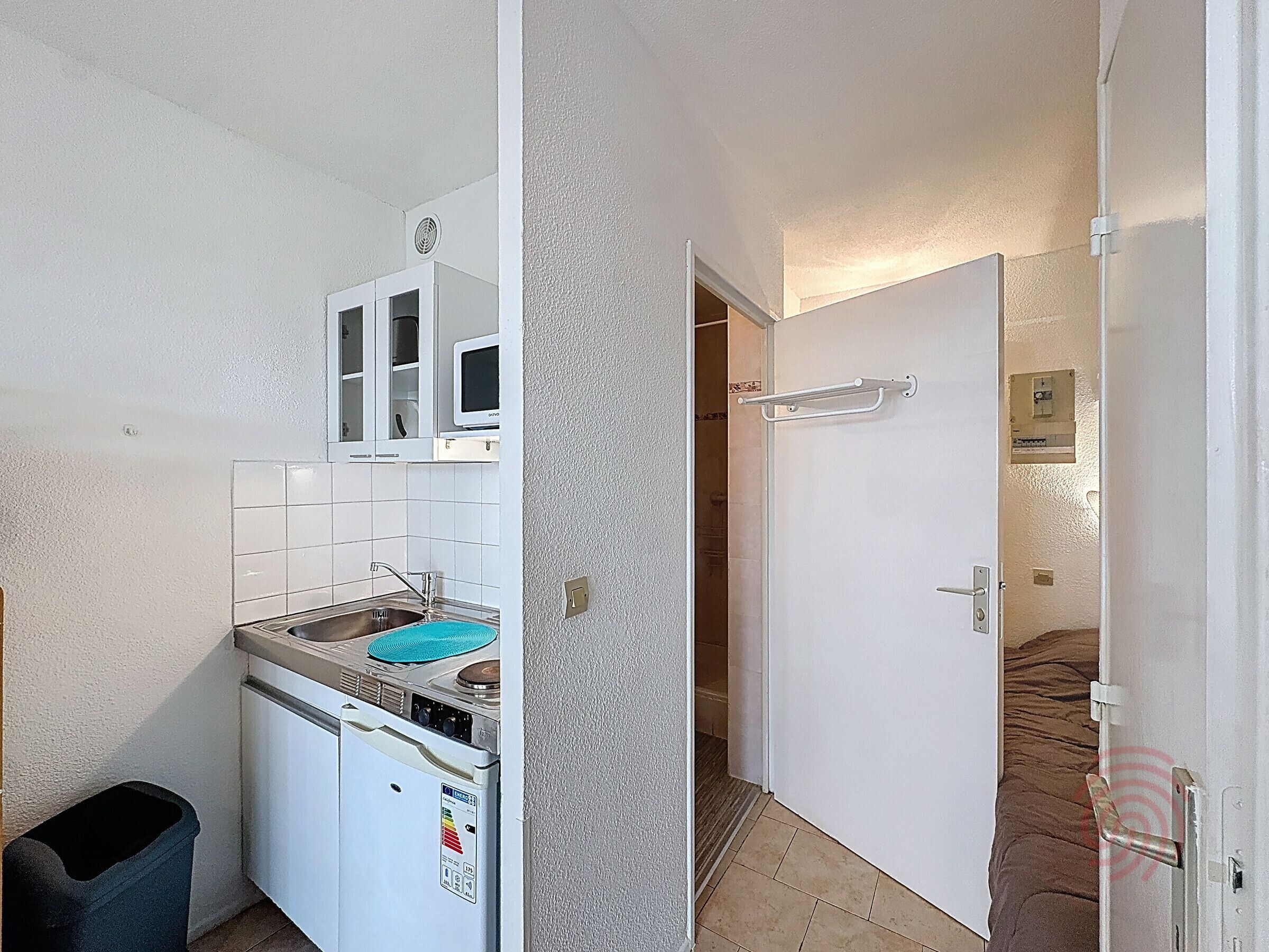 Une cuisine de taille réduite, équipée d’un évier, d’une cuisinière et de placards.