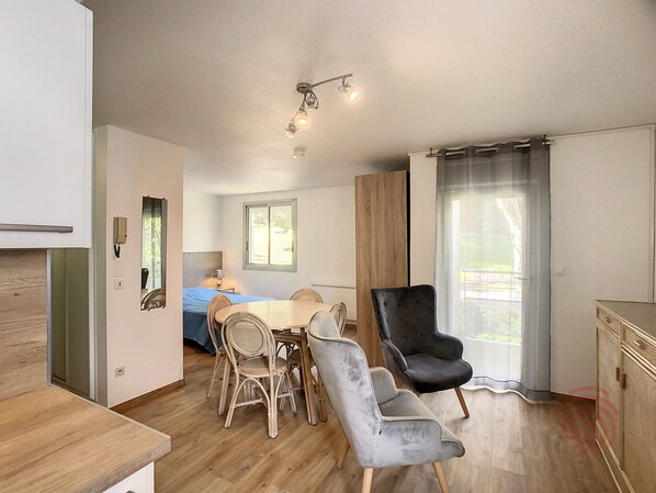 A modern living room with a dining area, a large window, and a view of the outdoors.