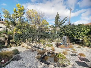 Un jardin avec un bassin, des marches en pierre et différentes espèces de plantes.