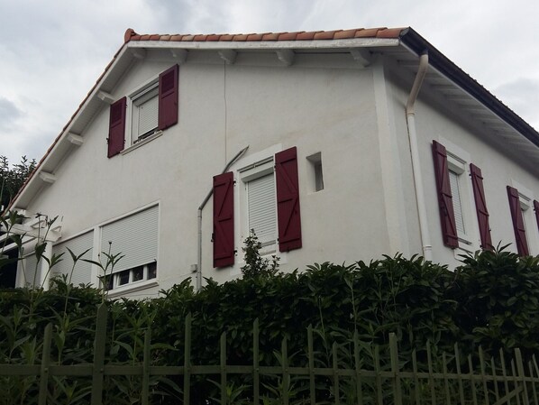 A two-story house with red shutters and a white facade.