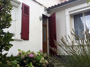 Une maison avec une porte, des volets rouges et une fenêtre.