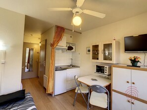 A compact kitchen with a microwave, oven, and a dining area with a table and chairs.