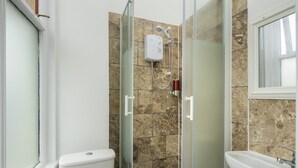 A bathroom with a glass-enclosed shower, a toilet, and a sink.