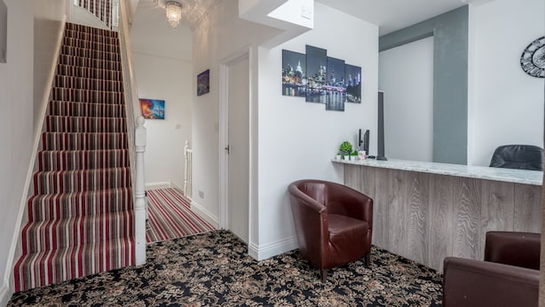 A staircase with red and white stripes, a reception desk, a brown leather chair, and a cityscape artwork on the wall.