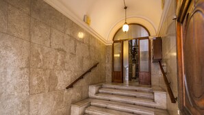 Una escalera de mármol con barandilla de madera, que conduce a una puerta con panel de vidrio.