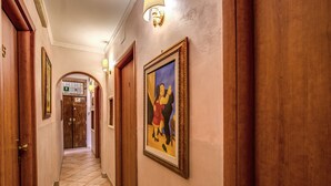 Un pasillo con puertas de madera, un cuadro enmarcado y suelo de baldosas.
