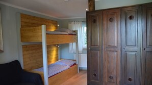 A bunk bed with a wooden headboard, a wardrobe with multiple doors, and a black chair. - Adele - Gästezimmer am Elberadweg (Dresden)