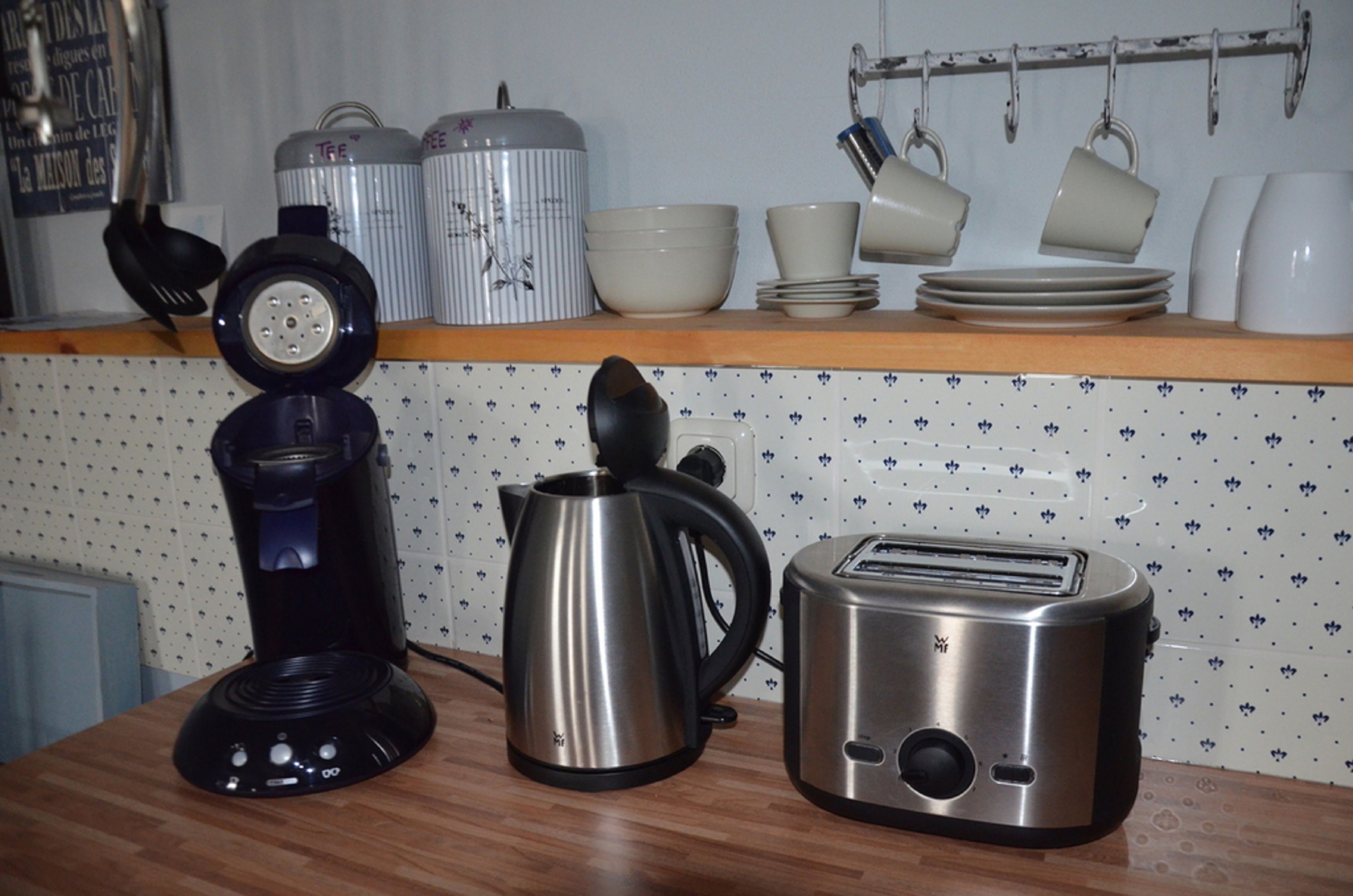 A kitchen counter with a coffee maker, kettle, and toaster.