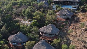 A resort with thatched-roof cottages surrounded by dense greenery. - Altamira Mazunte (Santa María Tonameca)