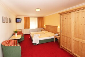 Une chambre d’hôtel équipée d’un lit, d’un bureau, d’une chaise, d’une armoire et d’un téléviseur fixé au mur.