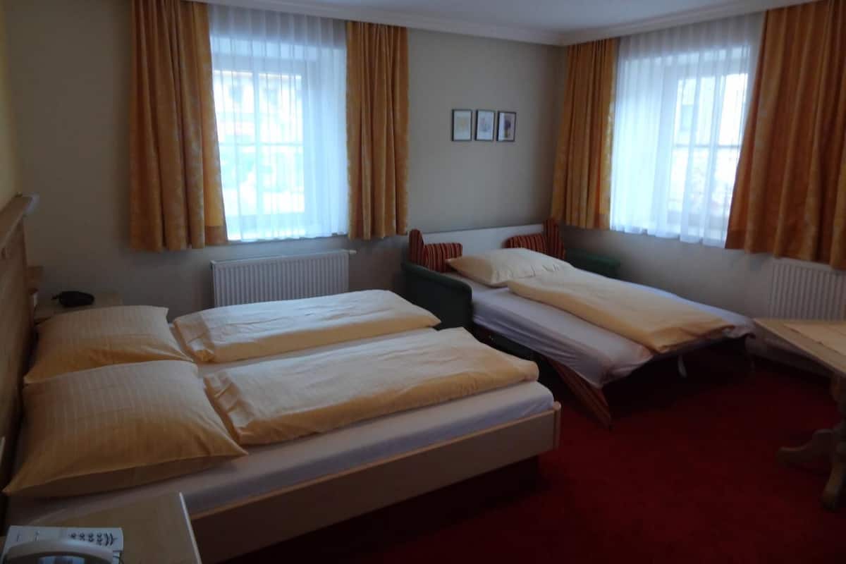 A hotel room with two single beds, a desk, and a chair.