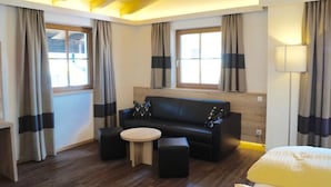 Ein modernes Hotelzimmer mit einer Couch, einem kleinen runden Tisch und einem Bett.
