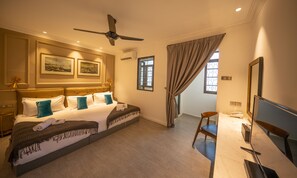A hotel room with a large bed, a desk with a chair, a ceiling fan, and two windows with curtains. - Reunion Residence (George Town)