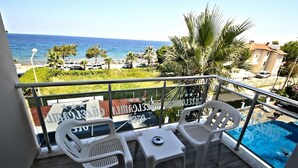 A balcony with two white plastic chairs, a small table, and a pool. - Oz Guzelcamli Otel (Kusadasi)