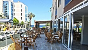 An outdoor patio with wicker furniture and a view of the sea. - Oz Guzelcamli Otel (Kusadasi)
