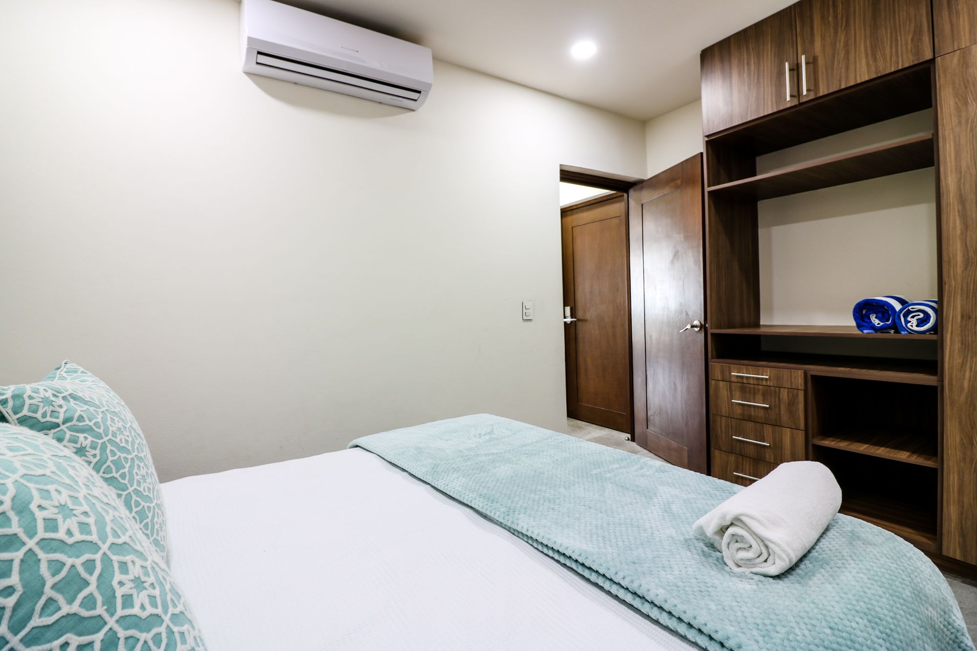 A bedroom with a bed, a wardrobe, and an air conditioning unit.