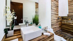 A modern bathroom with a wooden vanity, a large mirror, a white sink, and a shower area with a wooden wall. - The Furlough Fur201 (Playa del Carmen)