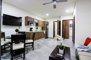 Una sala de estar moderna con comedor, cocina y televisor montado en la pared.