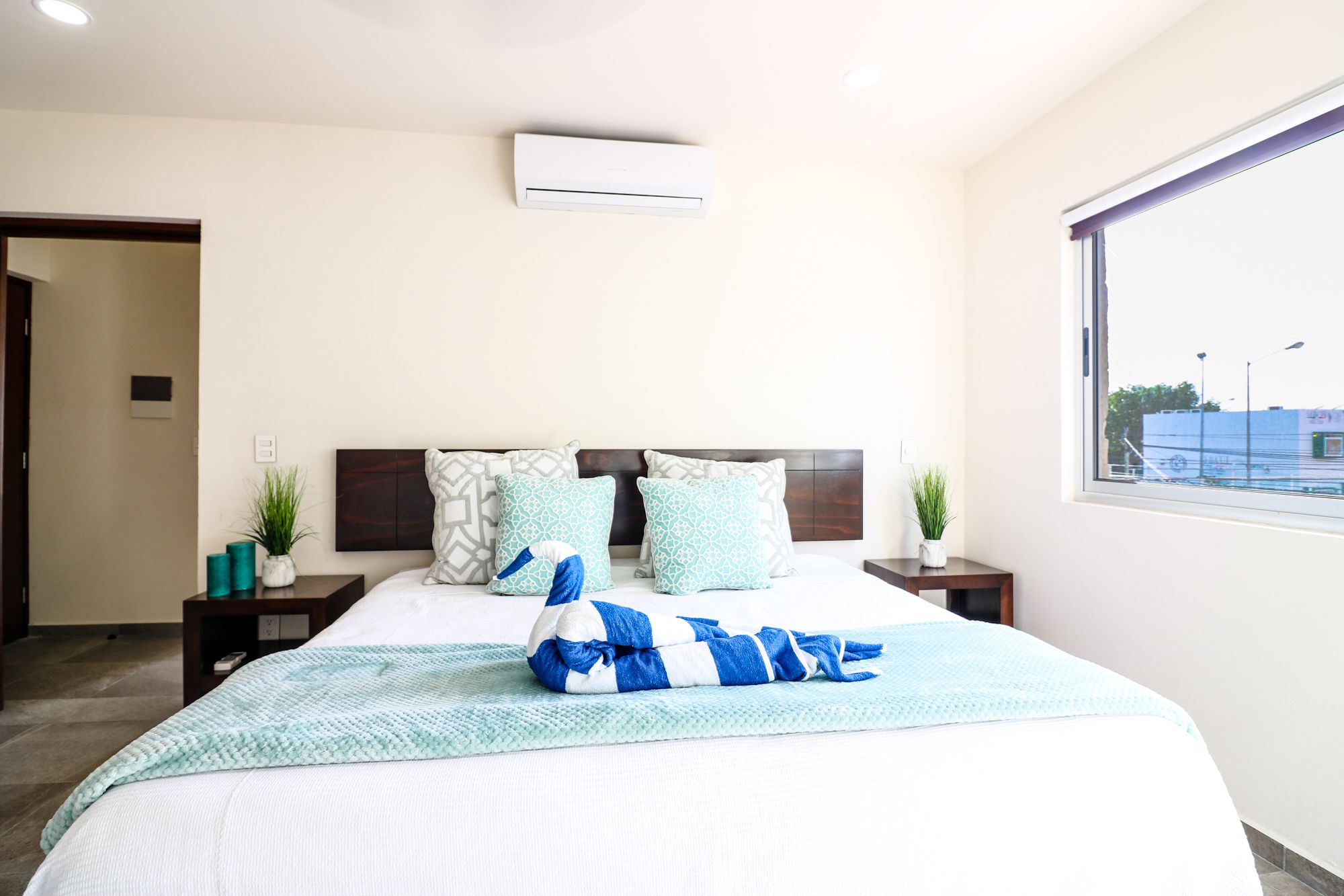 A hotel room with a bed, a window, and an air conditioning unit.