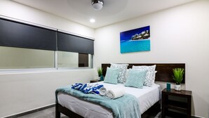Ein modernes Schlafzimmer mit einem großen Bett, einem Fenster, einem Nachttisch und einem Bild mit einer Strandansicht.